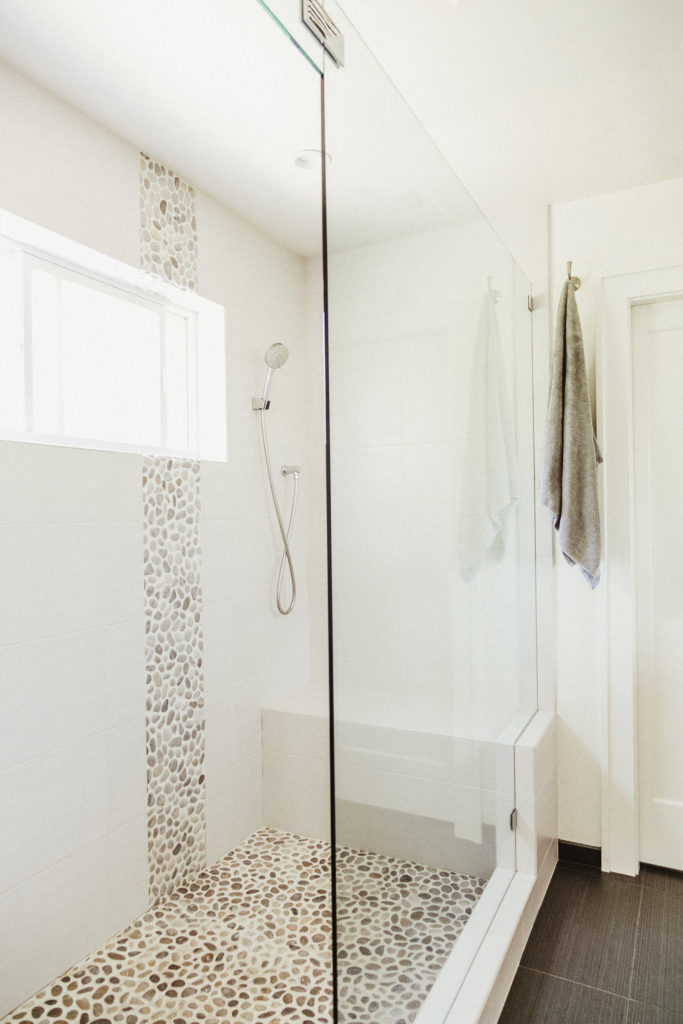 White tile walls, high window, glass wall and door, tiled built-in bench