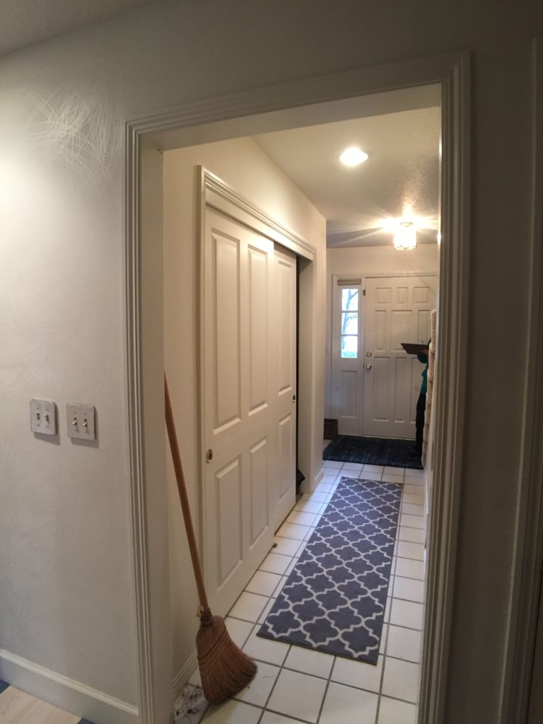 Looking toward front door past double wide closet, white walls and tile floor.