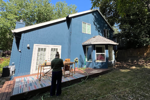 A blue, gabled house with a projecting bump-out breakfast nook into the yard.