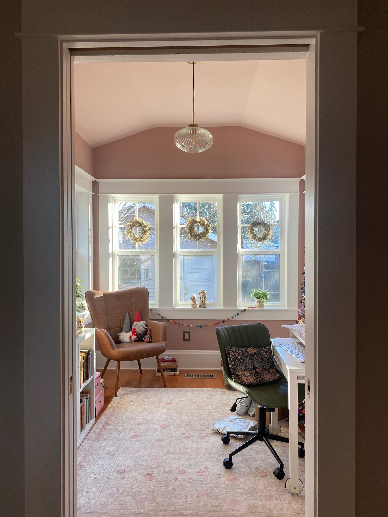 Looking into a small room with pink walls and four narrow windows looking out on a backyard.