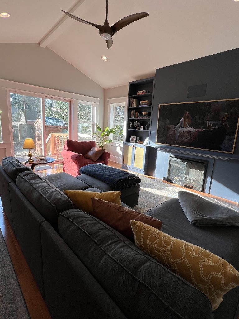 Vaulted ceiling living room with hearth feature and double doors leading to the backyard.