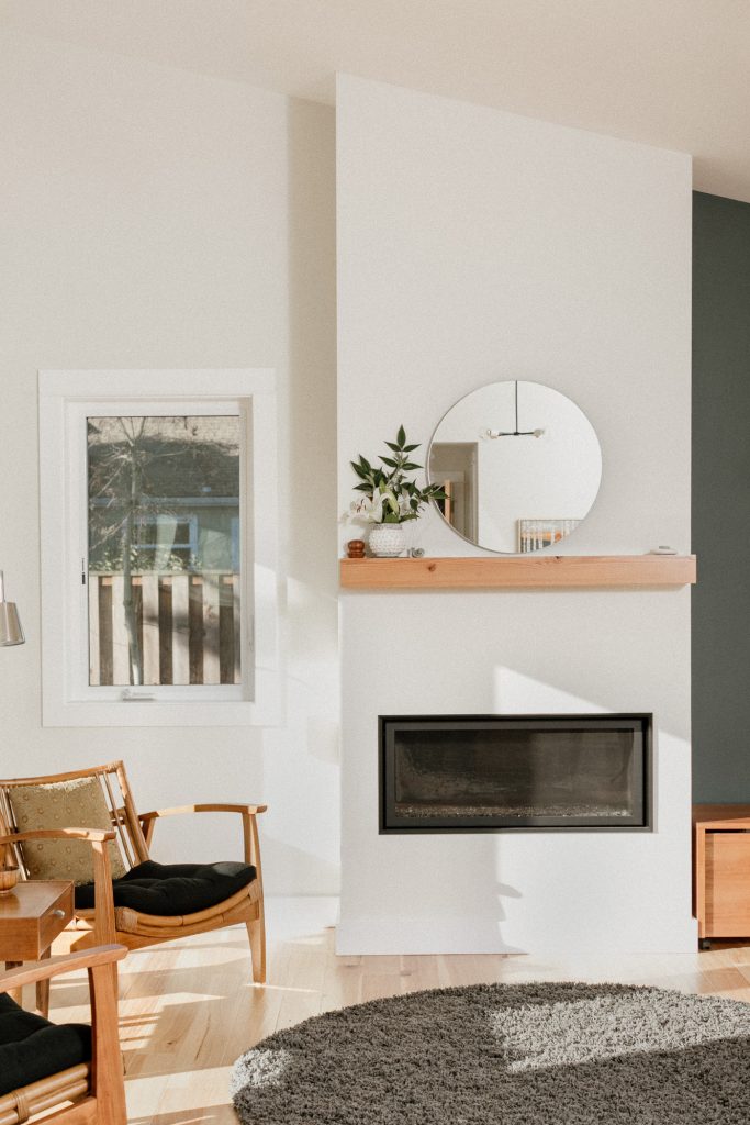 Light wood floors, white walls, mid-mod furniture, floating wood mantel over an electric hearth