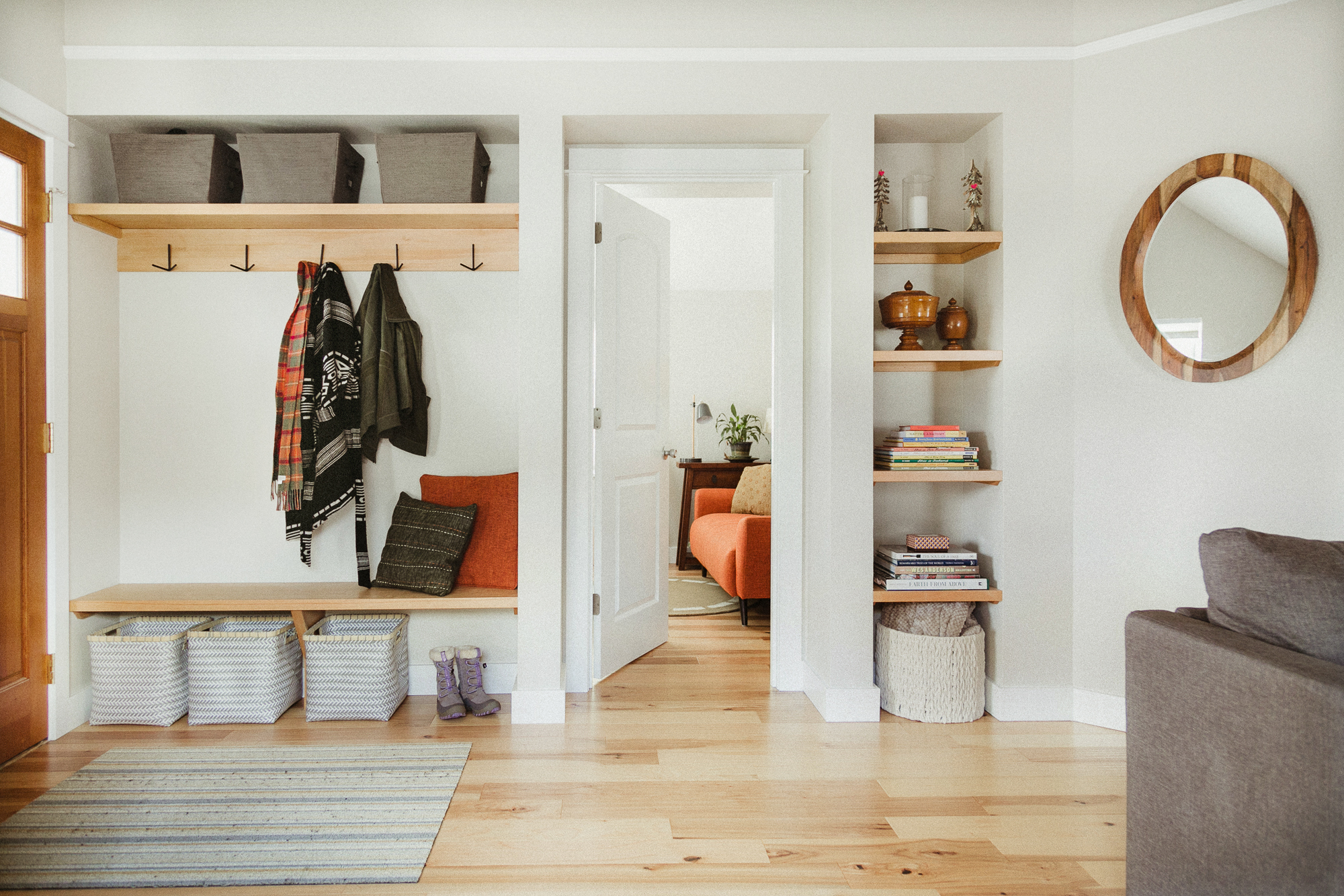 Light wood floors, natural wood shelves and bench, wrought-iron hooks, fabric storage bins.