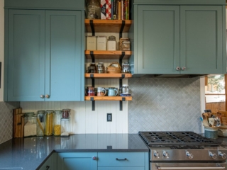Teal painted cabinets, cream narrow wainscoting backsplash, spices and decorative accents on the open shelving.